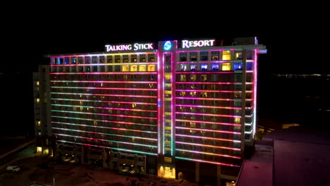 Orbiting-aerial-view-of-the-Talking-Stick-Resort-at-night-with-its-LED-wall-lighting-up