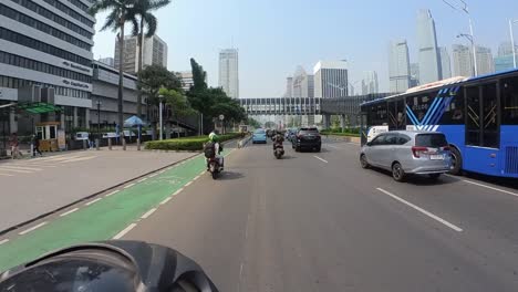 Motorcycles-and-cars-drive-through-the-busy-streets-of-Jakarta,-Indonesia-on-a-sunny-day