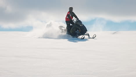 Schneemobilfahrer-Manövriert-Und-Gleitet-Auf-Schnee,-Lässt-Pulverschnee-In-Die-Luft-Gleiten