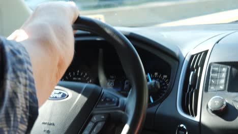 An-old-man-driving-a-ford-vehicle-with-hand-on-the-steering-wheel