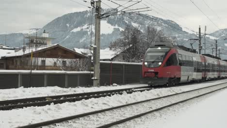 Wide-shot-of-a-train-driving-past-in-a-snowy-town