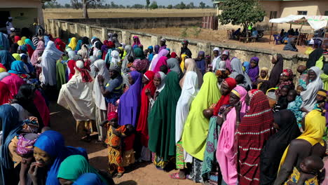 Afrikanische-Frauen-In-Farbenfroher-Kleidung-Und-Mit-Babys-Im-Arm-Stehen-Schlange,-Um-Humanitäre-Hilfe-Zu-Erhalten