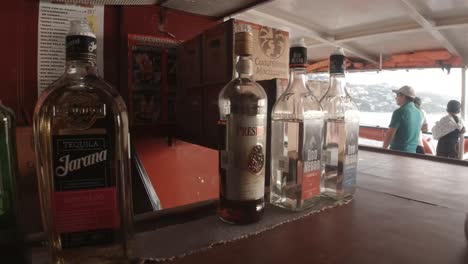 Bar-man-pick-up-Liquor-bottle-on-table-at-the-boat-bar,-pan-right