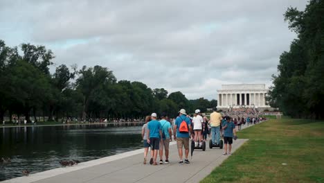 Group-Of-People-Walking-At-The-Promenade-Of-Reflecting-Pool-Of-Lincoln-Memorial-In-Washington-DC---slow-motion,-wide-shot