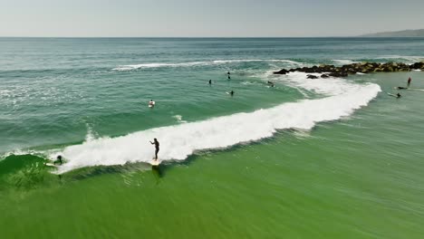 Drone-shot-surfers-ride-wave-in-sea-on-Venice-Beach-in-Los-Angeles