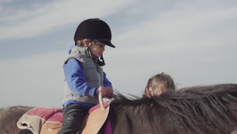 Kleiner-Junge-Genießt-Das-Reiten,-Während-Eine-Tiertrainerin-Das-Pferd-Führt