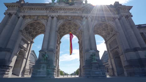 Upwards-angle-sideways-rotating-shot-of-the-Cinquantennaire-triumphal-arc-monument-in-Brussels,-Belgium,-on-warm-sunny-summer-day-with-blue-skies