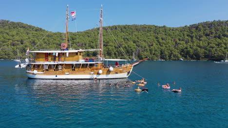 Gente-Relajándose-En-Inflables-Marinos,-Vacaciones-En-Velero,-Toma-De-Arco-Aéreo