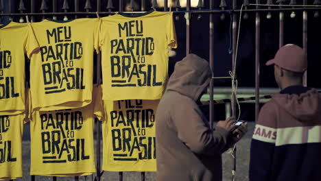 Street-Sellers-Exposing-Yellow-Shirts-of-Support-to-the-Elected-Brazilian-President-Jair-Messias-Bolsonaro-Celebrating-His-Victory-on-the-Pools-in-2018-at-Paulista-Avenue,-Sao-Paulo,-Brazil