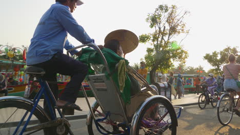 Una-Toma-De-Seguimiento-Detrás-De-Un-Turista-En-Un-Transporte-De-Alquiler-De-Bicicletas-Conduciendo-Por-La-Ciudad-De-Hoi-An-En-Vietnam