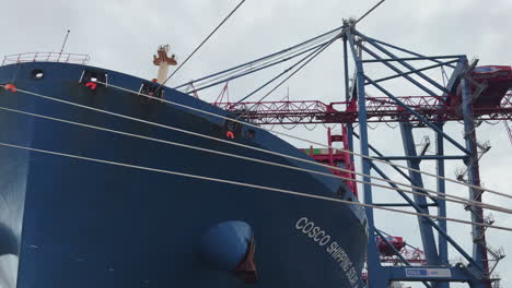 Low-angle-view-of-a-cargo-ship-being-loaded-by-a-crane-in-the-port-of-Hamburg