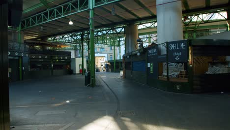 Lockdown-in-London,-desolate-shops-and-stores-in-empty-Borough-Market-hall-with-a-cinematic-sun-lens-flare-reveal,-during-the-coronavirus-pandemic-2020