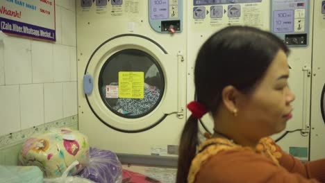 Lady-folding-clothes-in-Asian-Laundry,-Interior-Moving-shot,-Hanoi-Vietnam