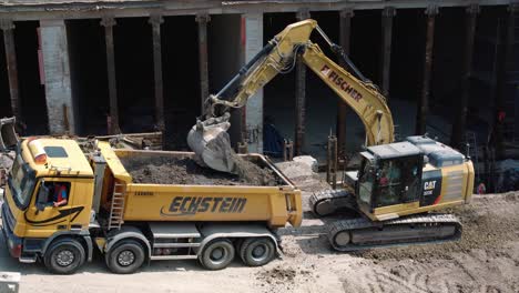 Bagger-Gräbt-Steine-Aus-Und-Lädt-Sie-Auf-Einer-Breiten-Baustelle-In-Einen-LKW