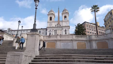 Subiendo-Las-Escaleras-Españolas-Casi-Vacías-Debido-Al-Covid-Con-La-Iglesia-De-La-Santissima-Trinità-Dei-Monti-Cuesta-Arriba,-Un-Famoso-Monumento-De-Roma,-Capital-De-Italia