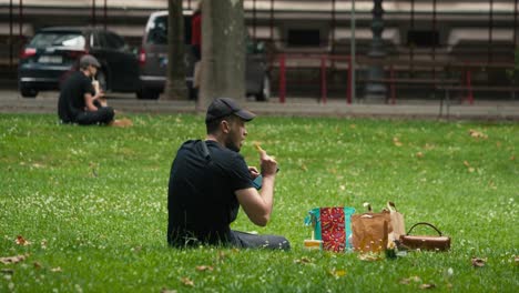 Hombre-Sentado-En-El-Césped-Usando-Una-Tableta,-Rodeado-De-Bolsas,-Durante-El-Cest-De-Zagreb-Es-El-Mejor-Festival-Callejero