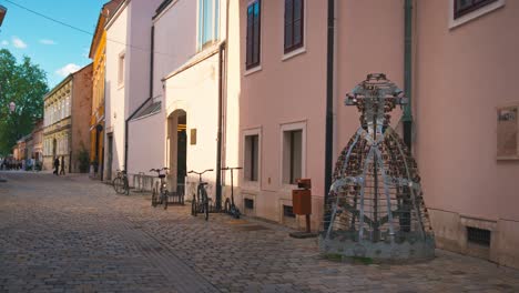 Crinoline-of-Love-sculpture-adorned-with-padlocks-on-a-cobblestone-street-in-Varaždin,-Croatia