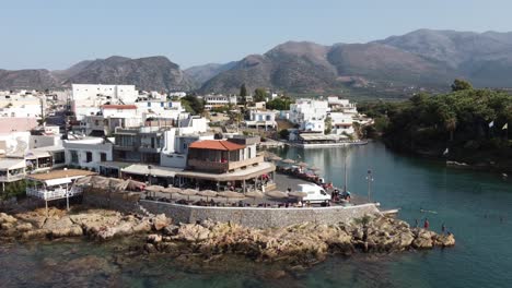 Drohne-Hoch-über-Der-Stadt-Sissi-Auf-Kreta,-Griechenland---Man-Sieht-Die-Stadt-Und-Den-Hafen-Im-Hintergrund-Die-Griechische-Landschaft