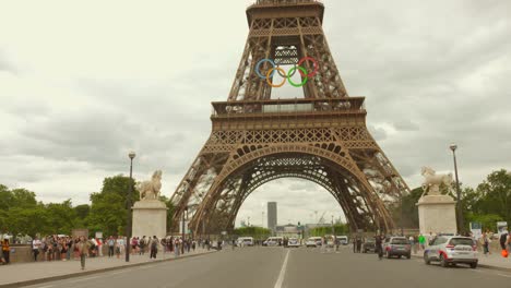 Tráfico-Al-Pie-De-La-Torre-Eiffel-Con-El-Logo-De-Los-Anillos-Olímpicos.