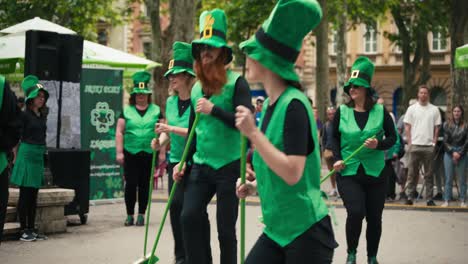 Un-Grupo-De-Artistas-Vestidos-Con-Trajes-Y-Sombreros-Verdes,-Bailando-Con-Escobas-En-El-Cest-De-Zagreb-Es-El-Mejor-Festival-Callejero.