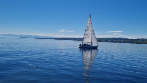 Yate-Navegando-En-El-Lago-De-Constanza-Con-Un-Cielo-Azul-Y-Alpes-Nevados-En-El-Horizonte