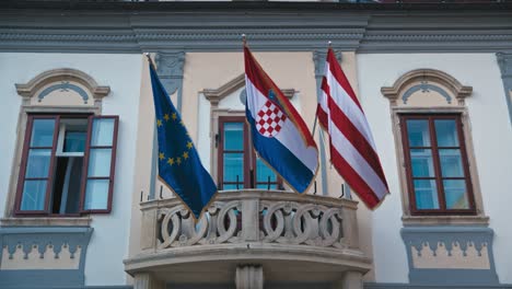 Las-Banderas-De-La-Unión-Europea,-Croacia-Y-Varazdin-Se-Exhiben-En-Un-Balcón-En-La-Plaza-Rey-Tomislav-En-Varazdin.