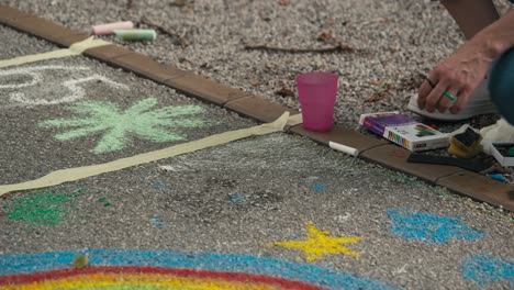 Person-creating-colorful-sidewalk-chalk-art-on-the-pavement-during-Zagreb's-Cest-is-d'Best-street-festival