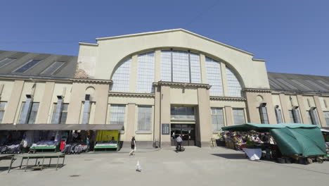 Exterior-establishing-pan-of-the-Riga-central-market-under-blue-sky-with-outdoor-stalls-and-stands