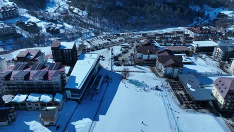 A-beautiful-aerial-view-of-a-snow-covered-village-surrounded-by-mountains,-showcasing-the-serene-and-tranquil-charm-of-a-winter-wonderland