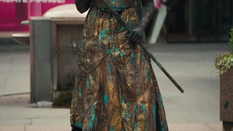 Street-performer-in-metallic-costume-and-makeup-posing-as-a-statue,-holding-a-staff,-at-Zagreb's-Cest-is-d'Best-street-festival