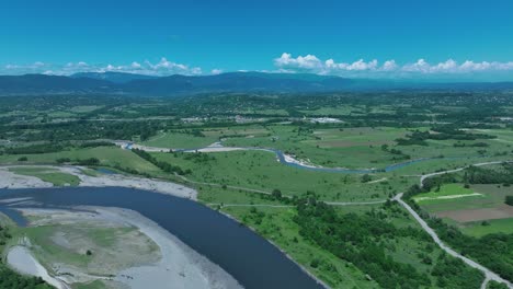 Luftaufnahme-Eines-Flusses,-Der-Sich-Durch-Eine-üppig-Grüne-Landschaft-Schlängelt,-Mit-Umliegenden-Feldern-Und-Natürlicher-Schönheit