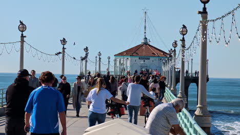 People-walking-in-slowmotion-on-a-bridge-on-a-wonderful-sunny-day,-Manhattan-Beach-with-copy-space