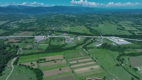 Aerial-view-of-a-scenic-river-surrounded-by-green-fields-and-distant-mountains,-capturing-the-tranquility-of-the-natural-environment