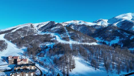 Una-Vista-Aérea-De-Una-Estación-De-Esquí-Cubierta-De-Nieve-Con-Pistas,-Alojamientos-E-Instalaciones,-Que-Muestra-Un-Vibrante-Destino-Para-Deportes-De-Invierno