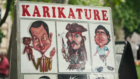 Colorful-caricatures-of-famous-personalities-displayed-at-Zagreb's-Cest-is-d'Best-street-festival,-under-a-sign-that-reads-"KARIKATURE