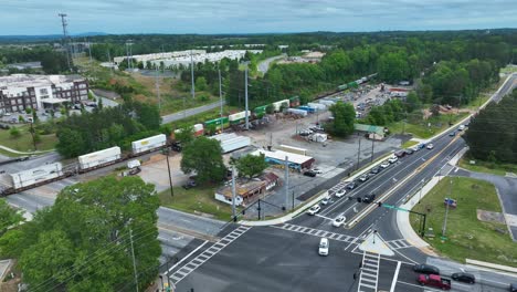 Aerial-view-of-industrial-cargo-container-train-on-track-beside-Highway-in-american-suburb