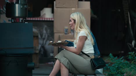 Two-women-sitting-on-a-bench,-eating-food-during-Zagreb's-Cest-is-d'Best-street-festival