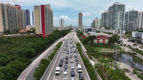 Sunny-Isles-Beach-traffic-on-a-busy-highway-surrounded-by-high-rise-buildings