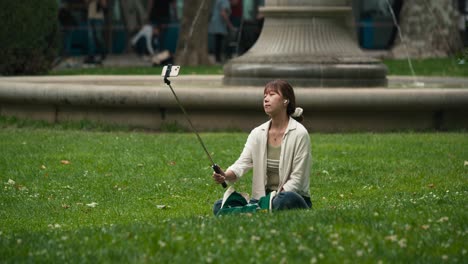 Woman-sitting-on-grass-using-a-selfie-stick-at-Zagreb's-Cest-is-d'Best-street-festival