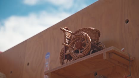 wicker-tricycle-sculpture-is-displayed-on-a-wooden-shelf-against-a-clear-blue-sky-at-the-Market-of-Traditional-Crafts-in-Varazdin