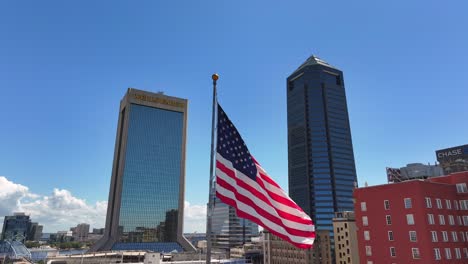 Downtown-Jacksonville-skyline-with-prominent-Wells-Fargo-and-Chase-buildings,-featuring-a-large-American-flag