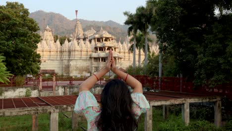 young-girl-praying-at-ancient-unique-temple-with-bright-sky-at-day-from-back-angle-video-is-taken-at-ranakpur-jain-temple-rajasthan-india