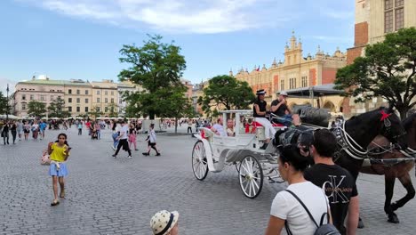 Amplia-Toma-De-Carruajes-De-Caballos-Populares-En-Las-Calles-De-La-Plaza-Principal-De-Cracovia-Por-La-Noche.