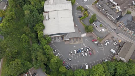 Drone-view-of-an-anonymous-UK-supermarket,-showing-the-exterior,-parking-lot,-and-nearby-roads