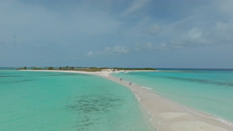 Drone-shot-of-people-walking-on-the-sand-bank-between-2-islands-at-Cayo-Agua,-Los-Roques,-Venezuela