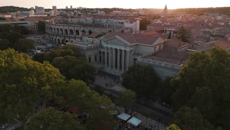 Aerial-of-Arènes-de-Nîmes-and-surrounding-historic-buildings-at-sunset,-showcasing-the-architectural-beauty-and-cultural-heritage-of-the-city