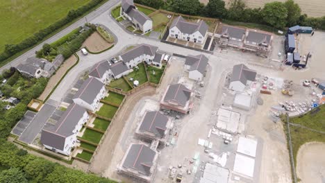 Drone-view-of-new-homes-being-built-in-a-rural-setting-in-Devon-UK,-surrounded-by-fields-and-countryside