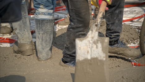 Slow-motion-of-a-group-of-unrecognizable-mexican-latin-construction-workers-flattening-fresh-concrete-mix-using-shovels