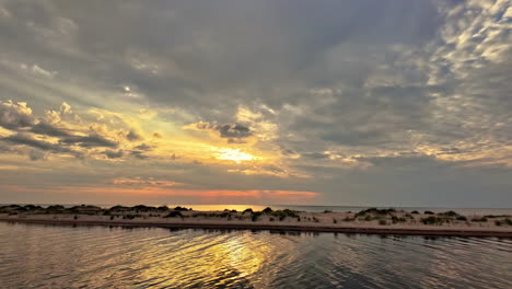 Hermosa-Puesta-De-Sol,-Relajantes-Olas-Lentas-En-La-Playa,-Reflejo-Del-Sol-Entre-Las-Nubes