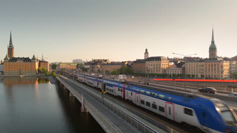 Trains-and-traffic-cross-Central-Bridge-between-Gamla-Stan-and-Södermalm,-drone